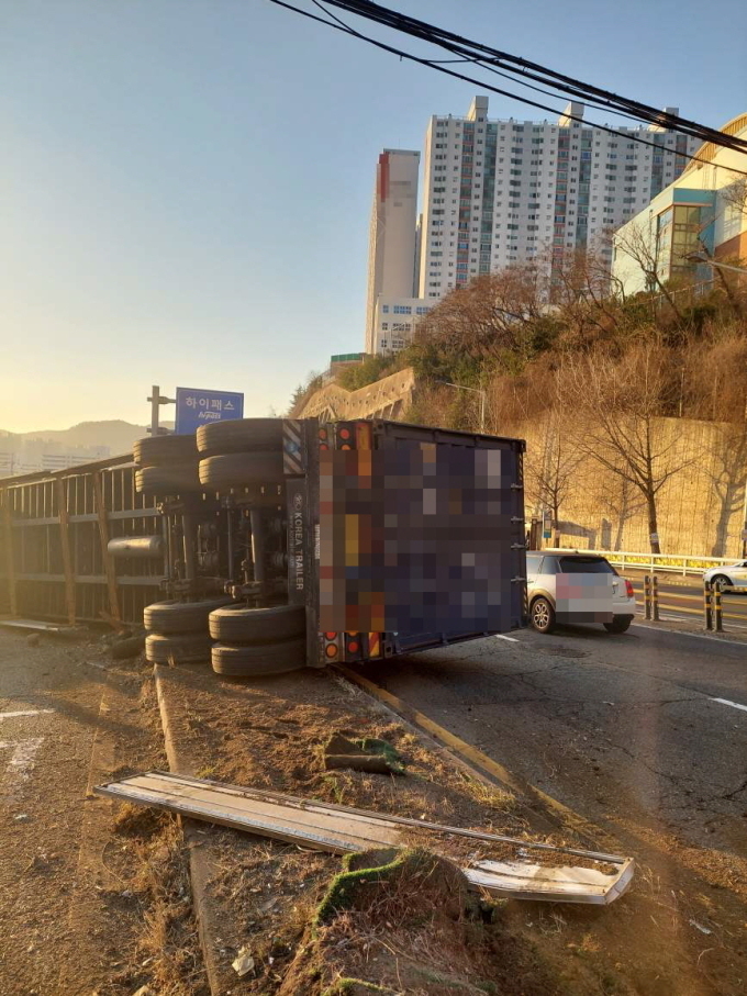12일 오전 7시53분쯤 부산 부산진구 백양터널 수정터널 방향 도로를 운행 중이던 30t 트레일러 차량이 중앙분리대를 넘어 옆으로 쓰러졌다. (사진=부산진경찰서 제공)
