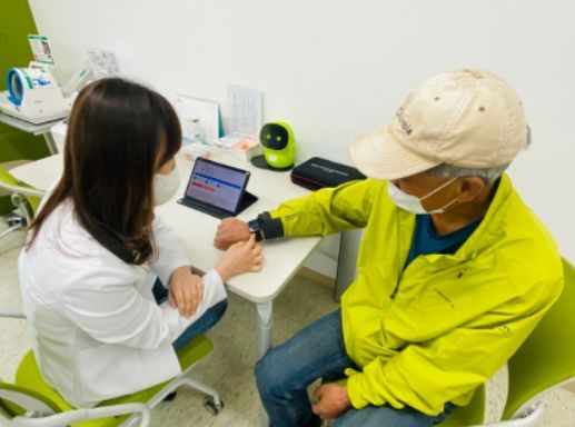 대상자에게 손목 활동량계 사용법을 알려주는 사진