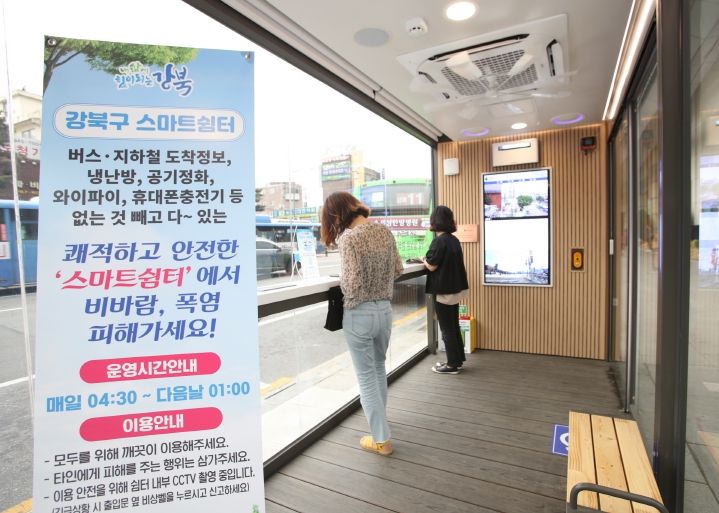 시민들이 쾌적한 강북구 스마트쉼터 안에서 버스를 기다리고 있다.