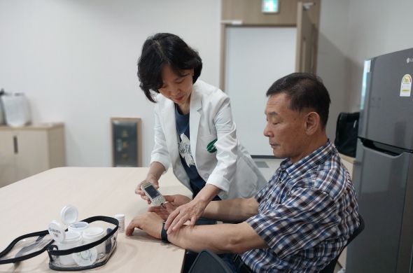 ‘AI·IoT 기반 어르신 건강관리 사업’에 참여 중인 한 어르신이 혈당 체크 후 기기를 통한 결과를 기다리고 있다.